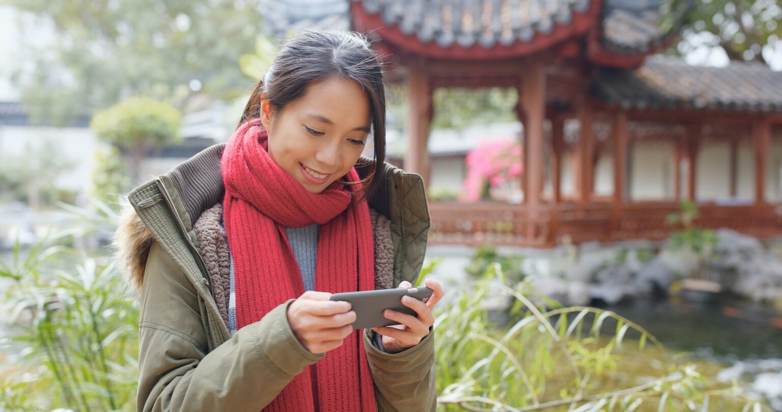 Woman use of smart phone in the chinese pavilion garden